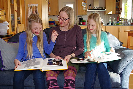 Mutter Renate Emehrer blättert mit ihren Kindern Johanna (li.) und Martha, damals beide 9, in Alben mit Babyfotos